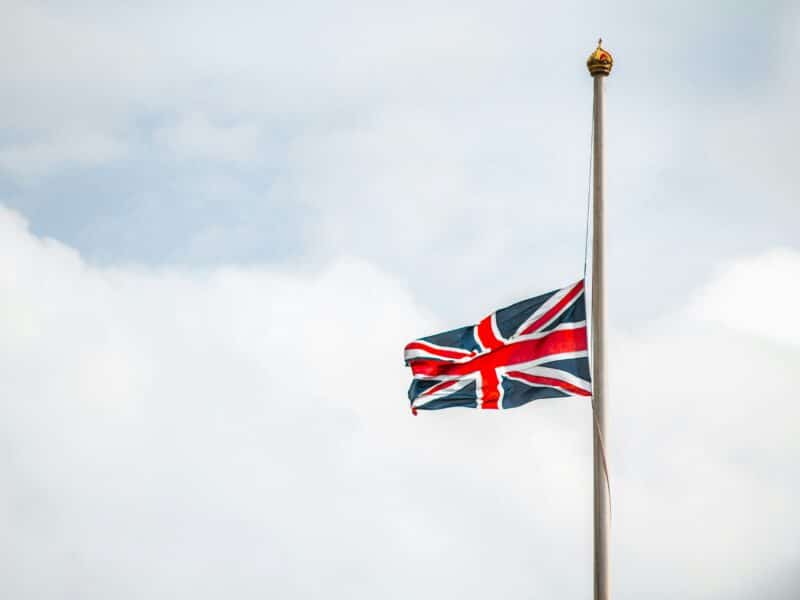 A UK flag is flying half-mast and waving in the wind.