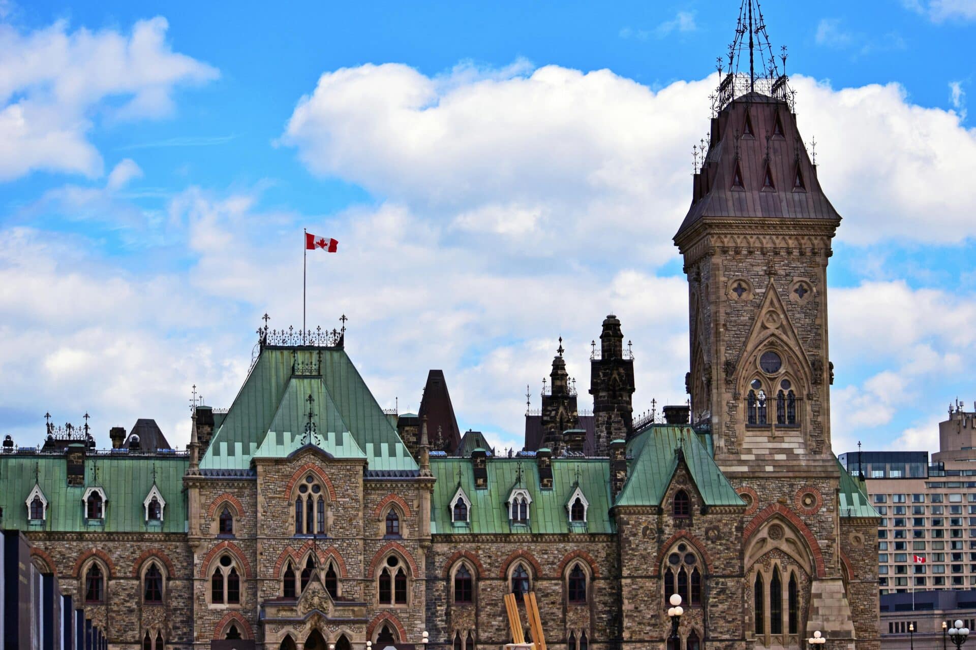 Parliament hill, Canada’s Parliament building, with a Canadian flag flying in the cloudy sky.