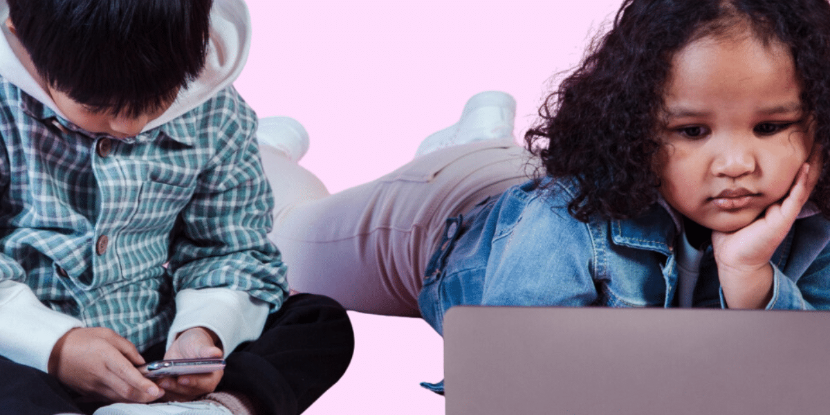 Two children are laying down on the floor staring at their respective devices.