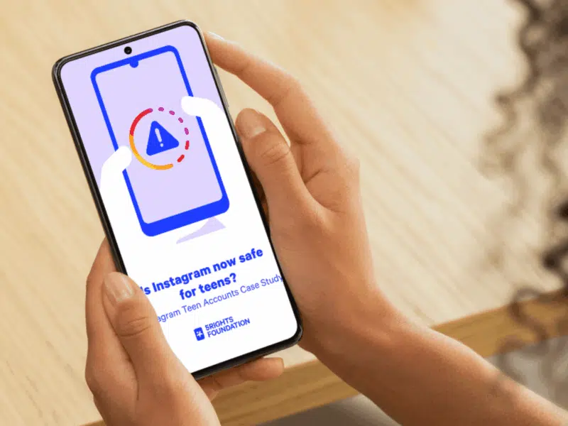 Person holding a smartphone displaying a screen with a warning icon inside an Instagram-style loading ring. The text on the screen reads: ‘Is Instagram now safe for teens’ Instagram Teen Accounts Case Study' with the 5Rights Foundation logo beneath it.
