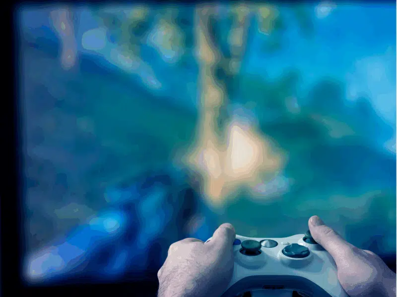 A wider shot showing both hands gripping a white video game controller, focused on a television screen with a blue-green blurred gaming scene in the background.