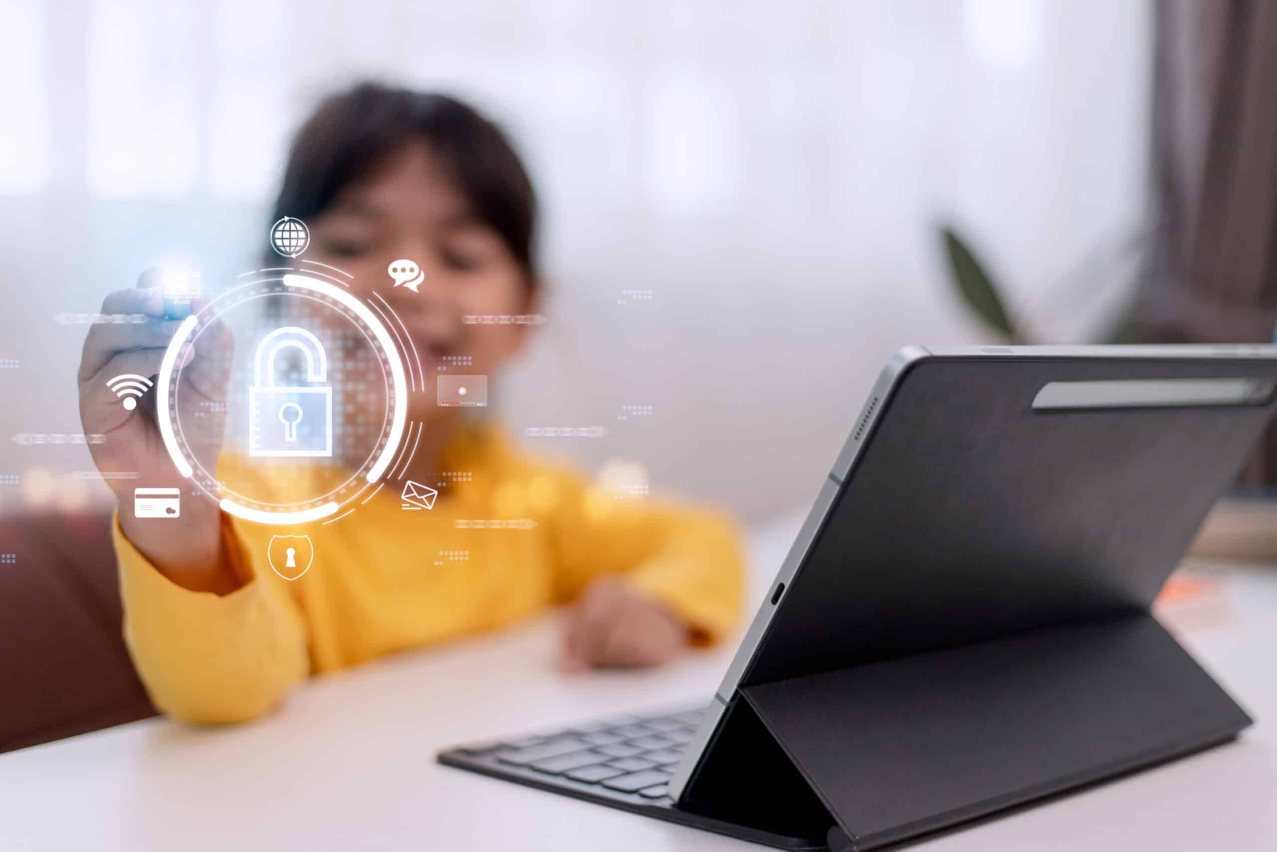 Little girl using laptop at home. icon of internet blocking app on foreground