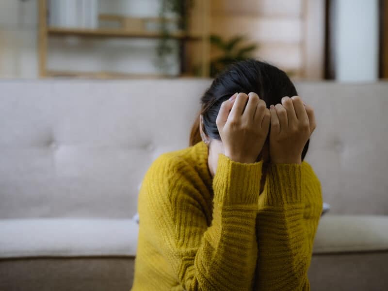young women with head in hands, upset.