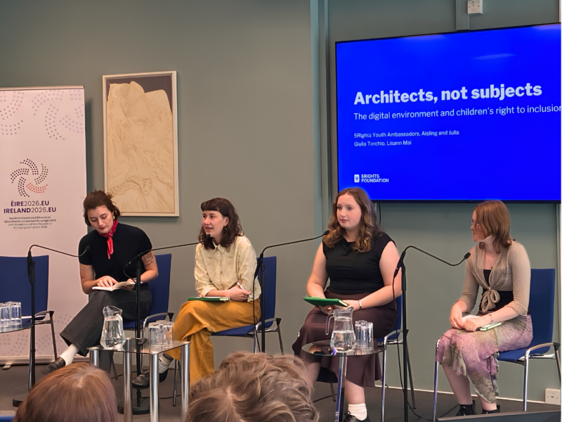 Giulia Torchio, Lisann Mai, and 5Rights Youth Council members Aisling and Julia sit on a panel in front of a screen reading "Architects, not subjects: The digital environment and children's right to inclusion," speaking at a conference on child participation organised by the Irish Presidency to the EU.
